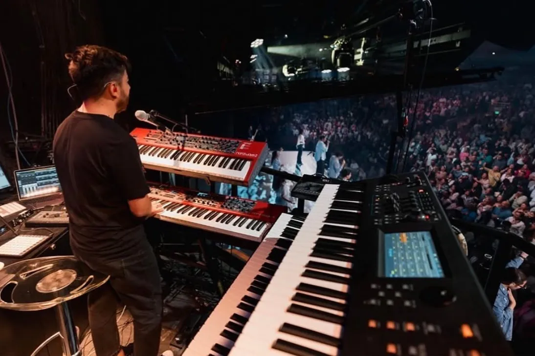 Sergio Bustos standing at his keyboard rig, facing a full auditorium